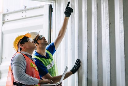 Uma pessoa segurando um notebook e outra apontando para cima.