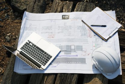 Capacete, notebook e planta de prédio
