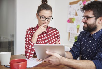 Controle de ponto remoto: colegas de trabalho sentados olhando tablet.