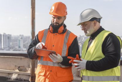 Entrega de epis: dois homens com equipamentos de proteção, como coletes e chapéus.