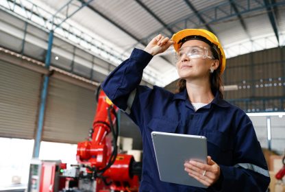 Profissional jovem funcionária de fábrica industrial trabalhando com peças de máquinas colocando, verificando e testando equipamentos industriais e a segurança do trabalho